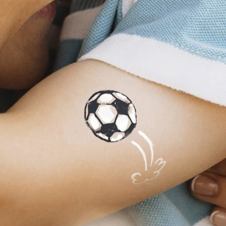 Zwart-witte tijdelijke voetbaltattoo met witte bewegingslijnen op de bovenarm van een kind.