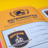 Detail van een pagina in het astronautenvriendenboek met een ruimte-embleem en invullijnen voor namen.